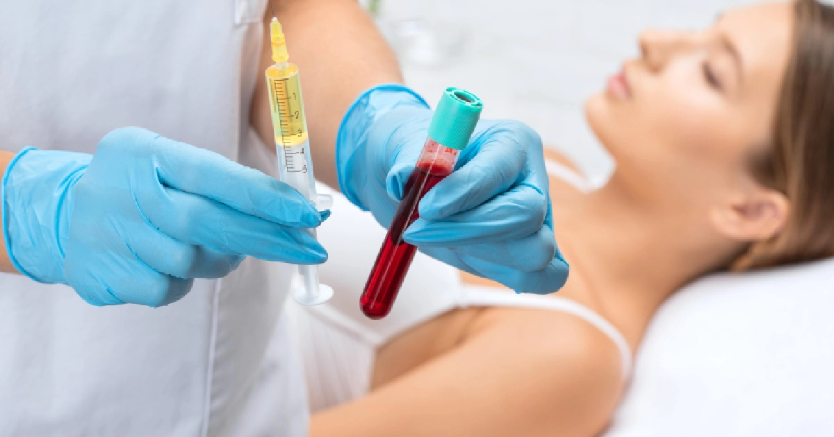 A gloved professional performs a PRP_PRF treatment in Fairview Park, Ohio, holding a syringe and blood tube as a patient lies on a treatment table.